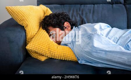 Stanco frustrato uomo millenario a casa, pensando ai problemi, sensazione di stress, fatica e mal di testa. Tristezza e vita infelice. Cheerl Foto Stock