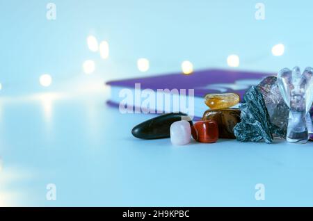 Primo piano angelo cristallo da quarzo chiaro vicino a una rivista luna con luci di Natale e incenso sullo sfondo. Concetto: Pratiche spirituali di cura di sé Foto Stock