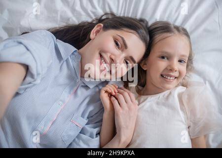 Bambino allegro e sua madre attraente in posa per la macchina fotografica Foto Stock