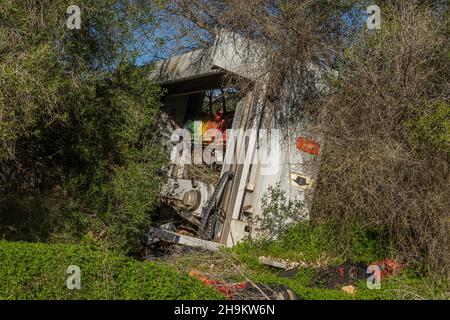 Lavatrice industriale abbandonata e disutilizzata in una foresta mediterranea in una giornata di sole. Immagine dell'incivismo che getta rifiuti in natura Foto Stock