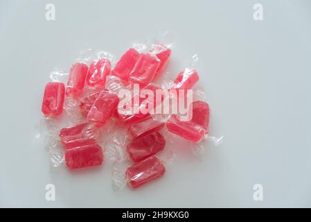 Caramelle rosse in involucro trasparente su sfondo bianco primo piano vista dall'alto con spazio di copia Foto Stock