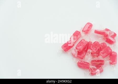 Caramelle rosse in involucro trasparente su sfondo bianco primo piano vista dall'alto con spazio di copia Foto Stock