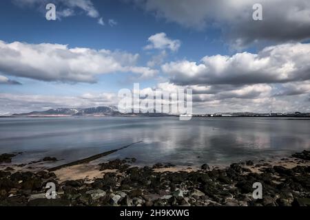 Un panorama roccioso della costa dell'oceano Atlantico, visto dalla penisola di Seltjarnarnes nella regione della capitale, Islanda. Niente persone, cielo nuvoloso. Foto Stock
