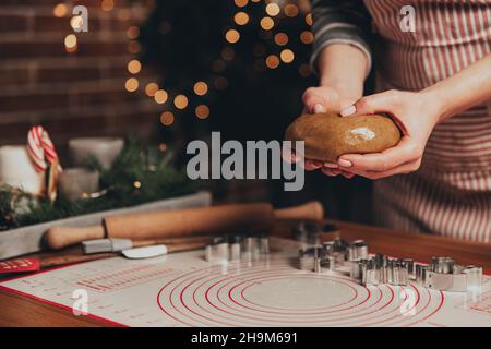 Buon Natale, Felice Anno Nuovo. Cottura del pan di zenzero, torta, biscotto o strudel. La donna in grembiule sta impastando l'impasto. Ragazza tenendola delicatamente, si piega, cuoca e cuocia. Decorazioni natalizie in cucina Foto Stock