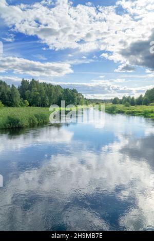 Paesaggio fiume Suprasl a Podlasie, Polonia. Il fiume scorre tra prati e boschi, il cielo blu con le nuvole bianche si riflette nell'acqua. Foto Stock