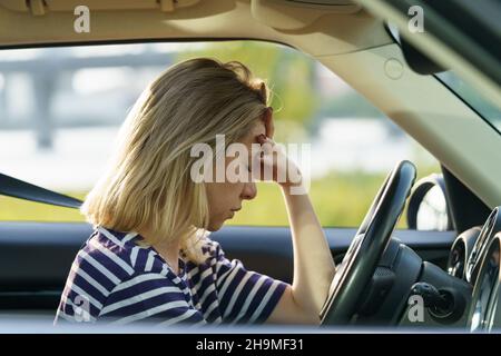 La donna depressa si siede in auto meditando sui problemi in famiglia, crisi di rapporto, burnout e stress Foto Stock