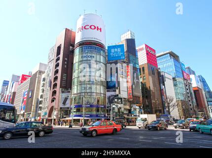 L'edificio Ricoh e altri edifici colorati nel cuore di Ginza, Tokyo, Giappone con taxi e altri veicoli al famoso incrocio di Ginza. Foto Stock