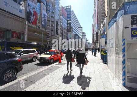 Chuo-dori Ave nel cuore di Ginza, Tokyo, con edifici alti, boutique di lusso, ristoranti e gente che cammina sulla strada. Foto Stock