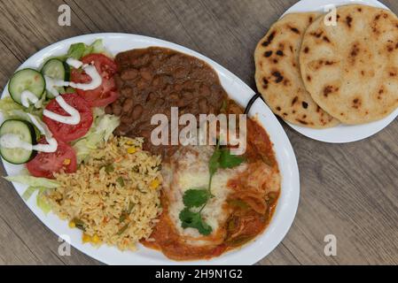 Vista dall'alto della generosa servitù del relleno aloong del cile con fagioli fritti, riso e pupupusa per il pasto al gusto di Latino. Foto Stock