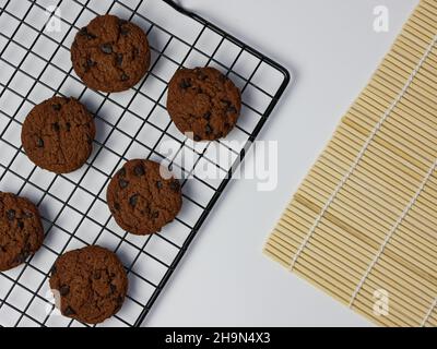 biscotti con scaglie di cioccolato su griglia di raffreddamento con sfondo bianco. Buongiorno, piatto, vista dall'alto Foto Stock
