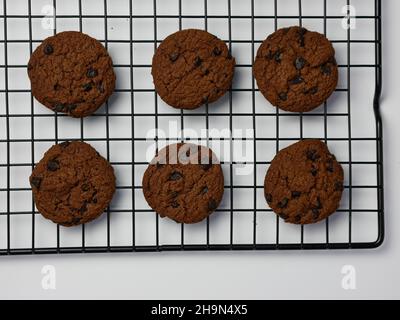 biscotti con scaglie di cioccolato su griglia di raffreddamento con sfondo bianco. Buongiorno, piatto, vista dall'alto Foto Stock