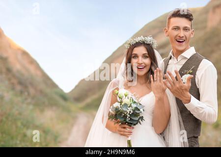 Happy sposi mostrando loro gli anelli di nozze all'aperto Foto Stock