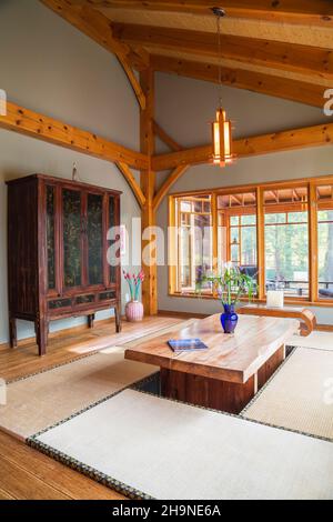 Tavolo da pranzo in legno rustico verniciato con tappetini in tatami, armoire cinese nero e marrone in sala da pranzo in stile giapponese all'interno della casa con struttura in legno. Foto Stock