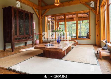 Tavolo da pranzo in legno rustico verniciato con tappetini in tatami, armoire cinese nero e marrone in sala da pranzo in stile giapponese all'interno della casa con struttura in legno. Foto Stock