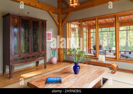 Tavolo da pranzo in legno rustico verniciato con tappetini in tatami, armoire cinese nero e marrone in sala da pranzo in stile giapponese all'interno della casa con struttura in legno. Foto Stock