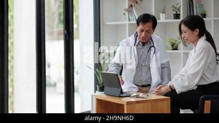 Medico asiatico senior consulenza giovane paziente femminile, parlando con il cliente alla visita di controllo medico. Trattamento di malattie geriatriche. Anziani Foto Stock