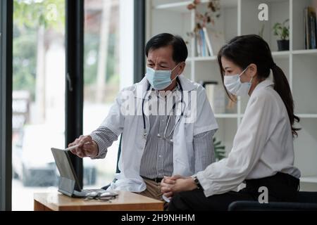 Medico asiatico senior consulenza giovane paziente femminile, parlando con il cliente alla visita di controllo medico. Trattamento di malattie geriatriche. Anziani Foto Stock