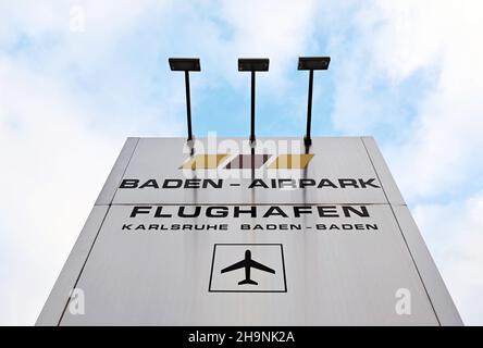 PRODUZIONE - 06 dicembre 2021, Baden-Wuerttemberg, Rheinmünster: Un pilone con l'iscrizione "Baden-Airpark Flughafen Karlsruhe Baden-Baden", presa prima di entrare in aeroporto. Prima il cambiamento climatico, poi Corona: Gli aeroporti regionali stanno vivendo un momento difficile. (A dpa 'solo un aeroporto per il paese? Aeroporti regionali sotto pressione') Foto: Uli Deck/dpa Foto Stock