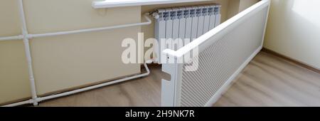 Batterie moderne per il riscaldamento. Radiatore bianco caldo con schermo protettivo. Concetto della necessità di un buon riscaldamento centralizzato. Foto Stock