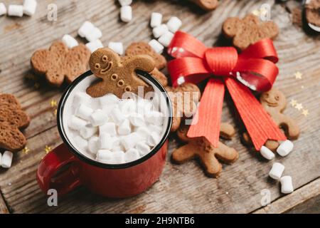 zenzero in una tazza di cacao con un grosso arco rosso su sfondo di legno, vista dall'alto. Vari dolci di Natale con una tazza di cacao sul tavolo. Natale Foto Stock