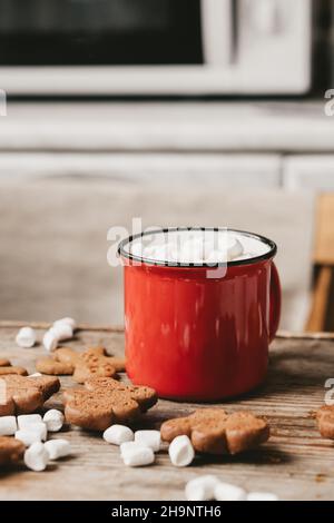 coppa rossa con cacao e marshmallows da vicino su sfondo di legno. Biscotti di Natale e altri dolci con cacao Foto Stock