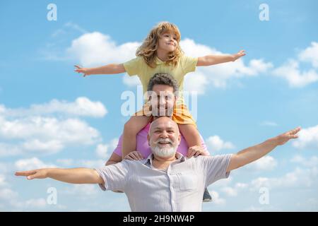 La famiglia generazionale. Padre, figlio e nonno felice famiglia multigenrazione con mani alzanti o braccia aperte che volano sul cielo. Foto Stock