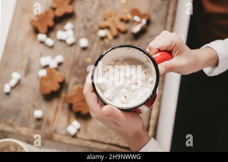 Una tazza di cacao con marshmallows primo piano, sullo sfondo dei biscotti di Natale. Dolci di Natale con cacao e marshmallow per i bambini su una w Foto Stock