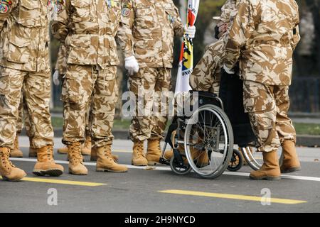 Bucarest, Romania - 1 dicembre 2021: Soldati veterani dell'esercito rumeno, di cui uno è ferito e disabile, seduti su una sedia a rotelle. Foto Stock