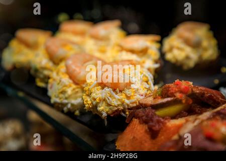 Tradizionale pintxos spagnolo di insalata russa o ensaladilla rusa con gamberi in mostra in un ristorante, San Sebastian Donostia, Paesi Baschi, Spagna Foto Stock