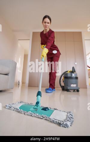 Donna dai capelli scuri in guanti di gomma che tagliano il soggiorno Foto Stock
