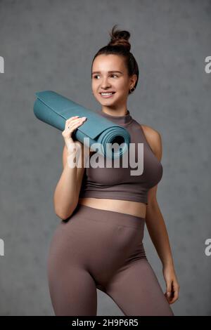 Donna incinta sorridente in abbigliamento sportivo pronto per la ginnastica mattutina o l'esercizio fisico. Giovane donna felice seguire stile di vita sano durante la gravidanza, tenere yoga Foto Stock