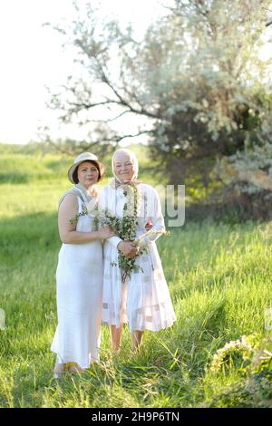 Ritratto di nonna con figlia che cammina all'aria aperta, indossando abiti bianchi. Foto Stock