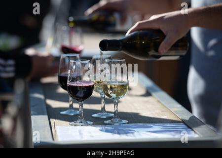Uomo che versa vino rosso e bianco in calici a gambo durante un laboratorio “Apero sur un plateau, vins & fromages” (degustazione di vino e formaggio) ad Alboussiere ( Foto Stock