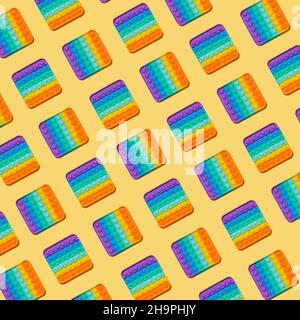 Motivo Popit su sfondo giallo. Popolare giocattolo in silicone colorato antistress pop it per bambini. Vista dall'alto. Semplice motivo a concavità Foto Stock