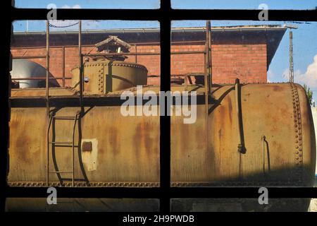 Vista attraverso la vetrata della fabbrica sul serbatoio diesel alla stazione, sala officina, locomotiva a vapore, vista dal capannone della locomotiva, vecchia stazione Hanau-Grossauheim Foto Stock