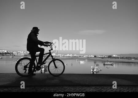 Silhouette di un ciclista nel porto di Ferragudo, fotografia in bianco e nero, bianco e nero, vista di Portimao, panorama della laguna, foce del Foto Stock