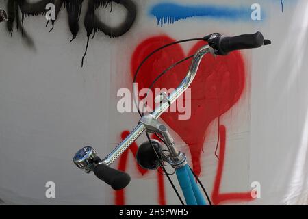 Manubri da bicicletta davanti al muro con il simbolo del cuore rosso, manubri da bicicletta davanti al cuore dipinto, forma del cuore, simbolo dell'amore, segno di Foto Stock