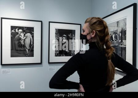 Londra, Regno Unito. 8 dicembre 2021. Un membro dello staff guarda le foto in anteprima di una mostra di fotografie perse dei Beatles di Lord Thynne, figlio della marchessa di Bath del 6th. La mostra, con immagini candide della band nella primavera del 1964 sul set del loro primo film A Hard Day’s Night, si trova alla Shapero Modern Gallery di Mayfair fino al 16 gennaio 2022. Credit: Stephen Chung / Alamy Live News Foto Stock