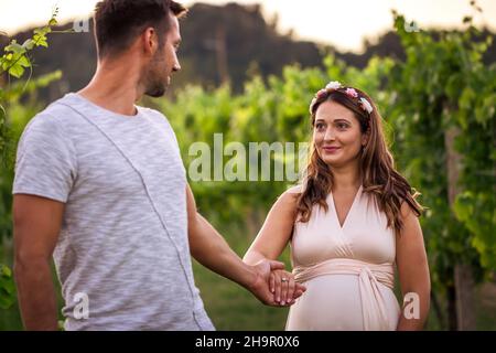Seguimi nel viaggio della vita. Donna incinta che tiene le mani con la sua partner. Giovane coppia all'aperto Foto Stock
