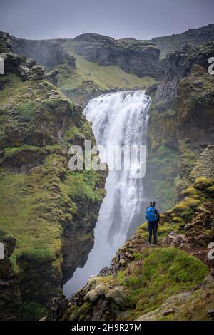 Escursionisti a una cascata in una gola, paesaggio a Fimmvoerouhals sentiero escursionistico, Islanda del Sud, Islanda Foto Stock