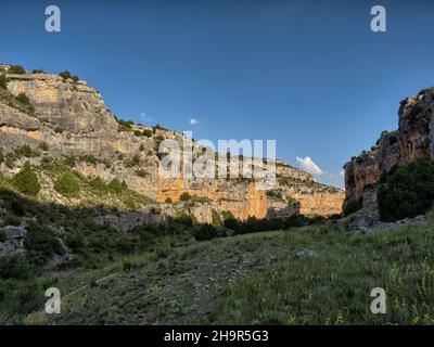 Vista delle pareti di roccia rossa a 'Barranco de la Hoz Seca' a Jaraba (Saragozza) durante una giornata nuvolosa d'estate. Foto Stock