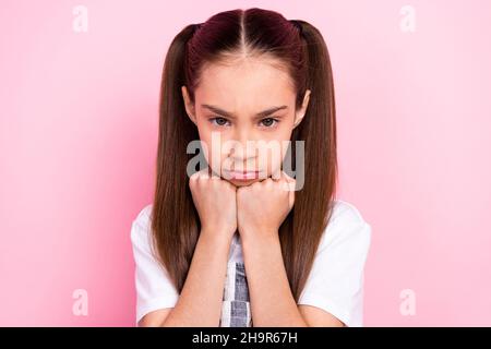 Ritratto di piccola ragazza con code triste grumpy infelice ottenuto cattivo umore isolato su sfondo color rosa pastello Foto Stock