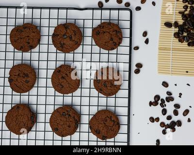 biscotti con scaglie di cioccolato su una griglia con chicchi di caffè su sfondo bianco. Buongiorno, piatto, vista dall'alto Foto Stock