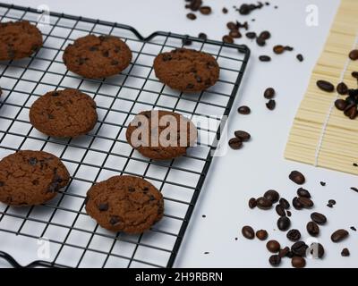 biscotti con scaglie di cioccolato su una griglia con chicchi di caffè su sfondo bianco. Buongiorno. Foto Stock