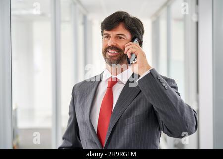 Uomo d'affari come imprenditore o consulente che parla al telefono con lo smartphone in ufficio Foto Stock