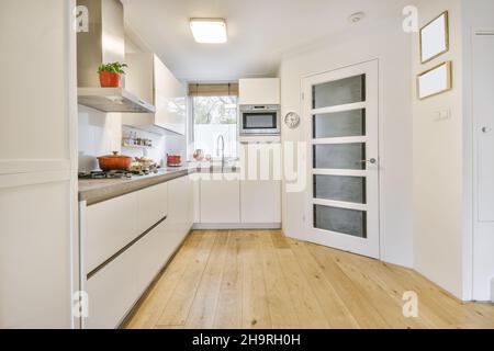 Accogliente cucina con mobili bianchi e pavimenti in legno Foto Stock