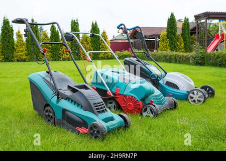 I tosaerba sono in piedi sul prato nel cortile del giardino. Un primo piano di un rasaerba elettrico. Foto Stock