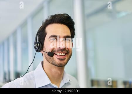 Uomo d'affari con cuffie che parla con un cliente come rappresentante del servizio clienti nel call center Foto Stock