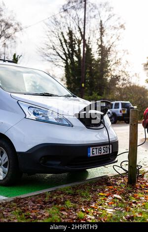 Woodbridge Suffolk UK Novembre 28 2021: Nissan e-NV200 furgone elettrico carica alla presa di carica in un parcheggio pubblico a Suffolk, Regno Unito Foto Stock