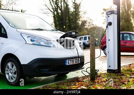 Woodbridge Suffolk UK Novembre 28 2021: Nissan e-NV200 furgone elettrico carica alla presa di carica in un parcheggio pubblico a Suffolk, Regno Unito Foto Stock